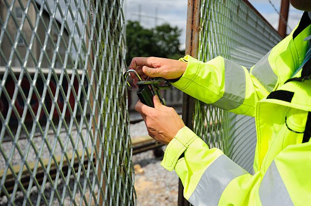 Subway area, man opening the locked wire fence, removing lock and chain.